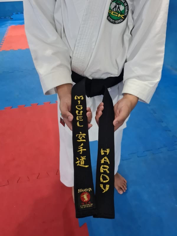 A faixa preta aberta, com Miguel, 空手道 e Hardy bordados em dourado